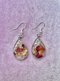 a pair of earrings with red and yellow flowers in them
