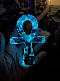 a person holding a glowing ankh in their hand